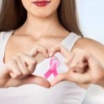 Confident breast cancer survivor after breast reconstruction surgery smiling in front of mirror